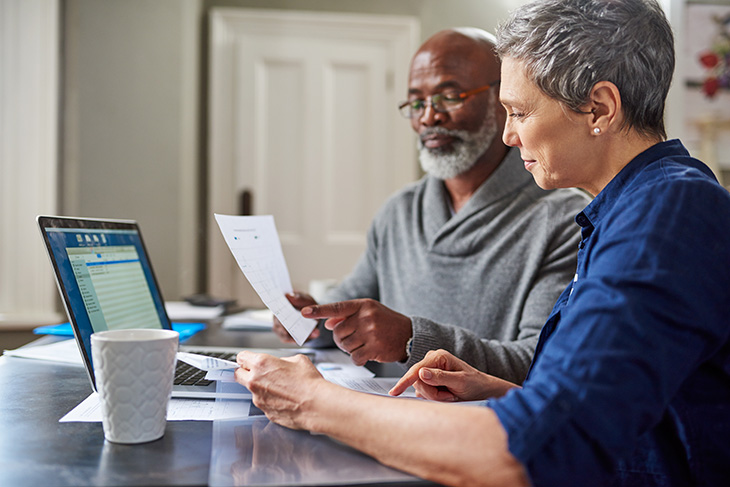 couple looking at finances with a laptop in front of them.