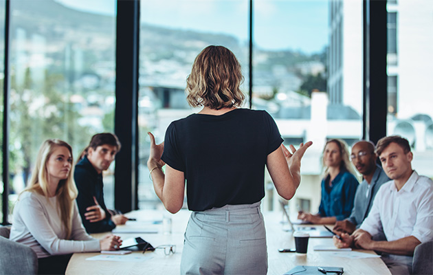 woman leader speaking to her team sitting around a table