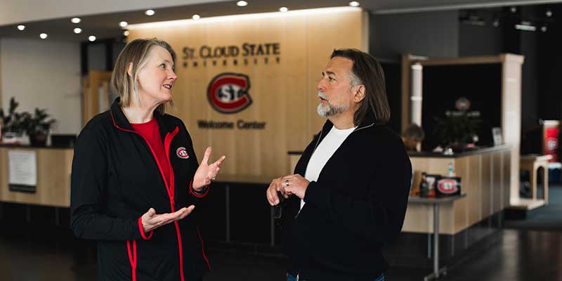 A woman and a man chatting in the Welcome Center lobby